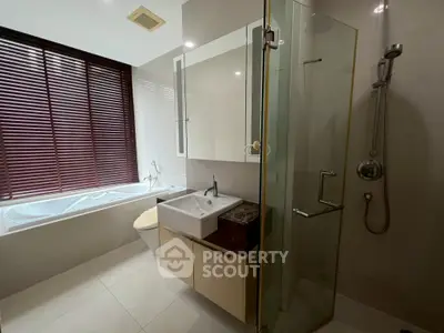 Modern bathroom with glass shower and bathtub, featuring sleek design and natural light.