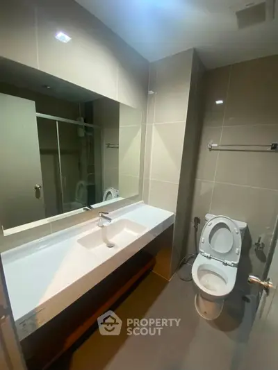 Modern bathroom with sleek fixtures and large mirror in contemporary apartment.