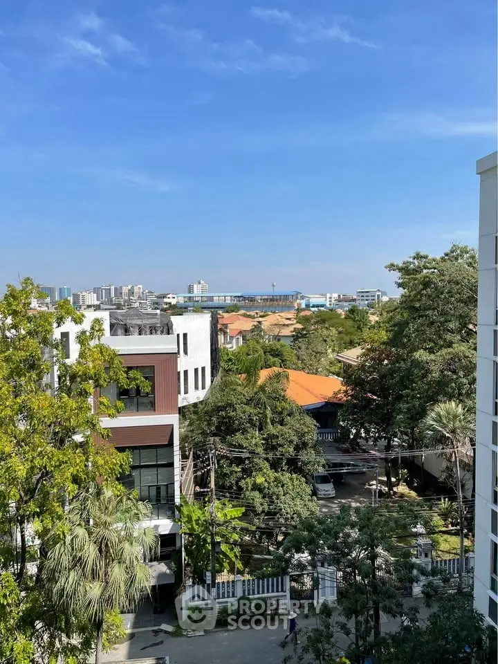 Stunning urban view from a high-rise building with lush greenery and clear blue skies.