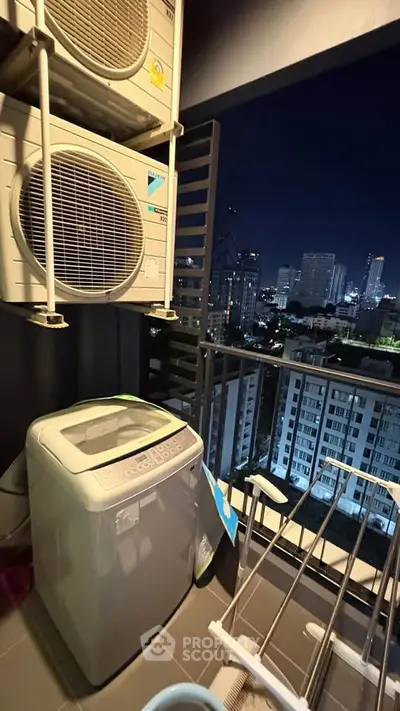 High-rise balcony with city view, featuring washing machine and air conditioning units.