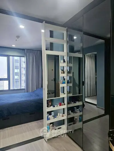 Modern bedroom with mirrored sliding doors and city view, featuring sleek storage solutions.