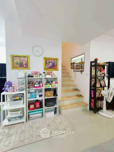Charming living space with staircase, bookshelves, and decorative accents in a cozy home setting.