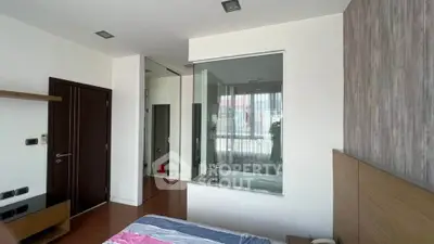 Modern bedroom with glass partition and ensuite bathroom featuring a bathtub.