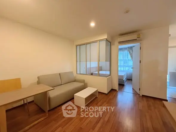 Modern apartment with cozy living room and bedroom, featuring wooden flooring and stylish decor.