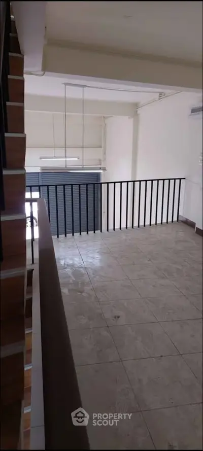 Spacious interior with tiled flooring and modern railing, ideal for versatile use.