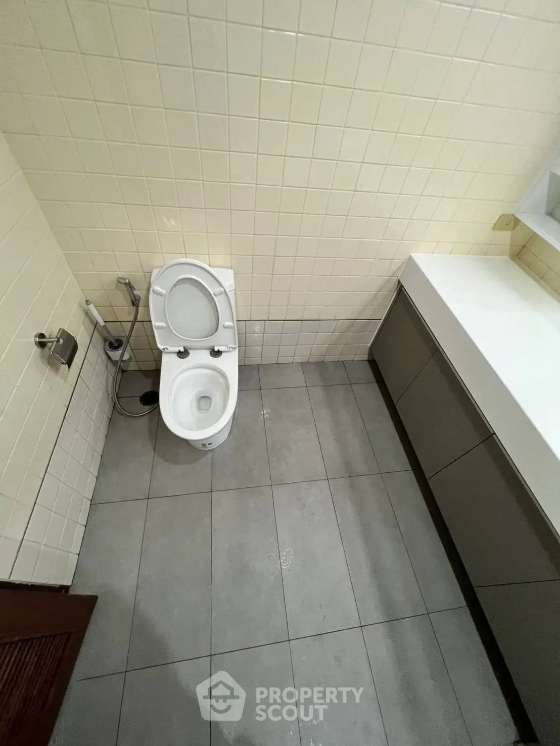 Modern bathroom with sleek fixtures and tiled walls, featuring a toilet and vanity unit.