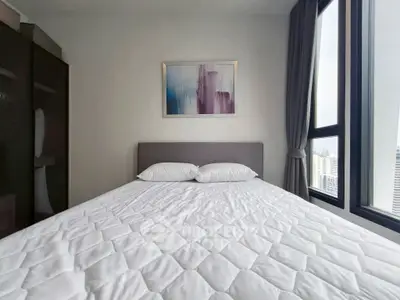 Modern bedroom with large window and stylish decor in urban apartment.