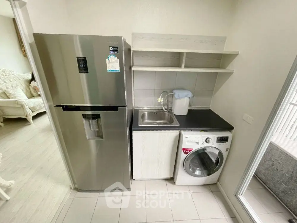 Modern kitchen with stainless steel fridge and washing machine in compact layout.