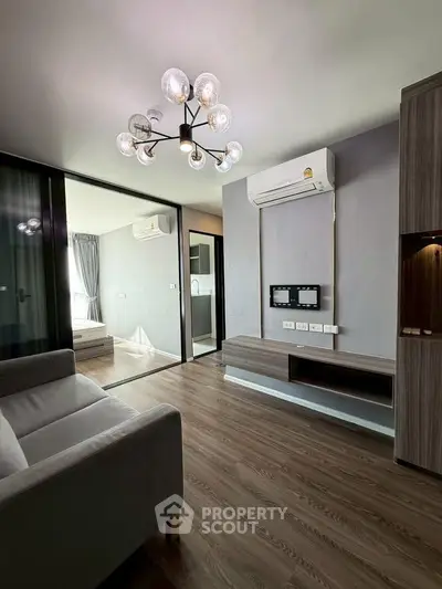 Modern living room with sleek design, featuring a stylish chandelier and air conditioning, perfect for urban living.
