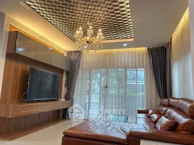 Luxurious living room with elegant chandelier and modern leather sofa, featuring a stylish TV unit and large windows.