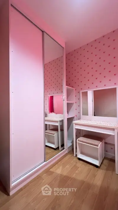 Charming pink-themed bedroom with mirrored wardrobe and vanity set.