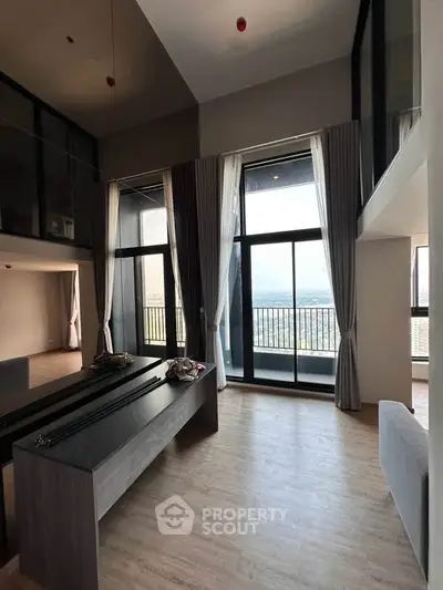 Spacious modern living room with floor-to-ceiling windows and balcony offering stunning views.