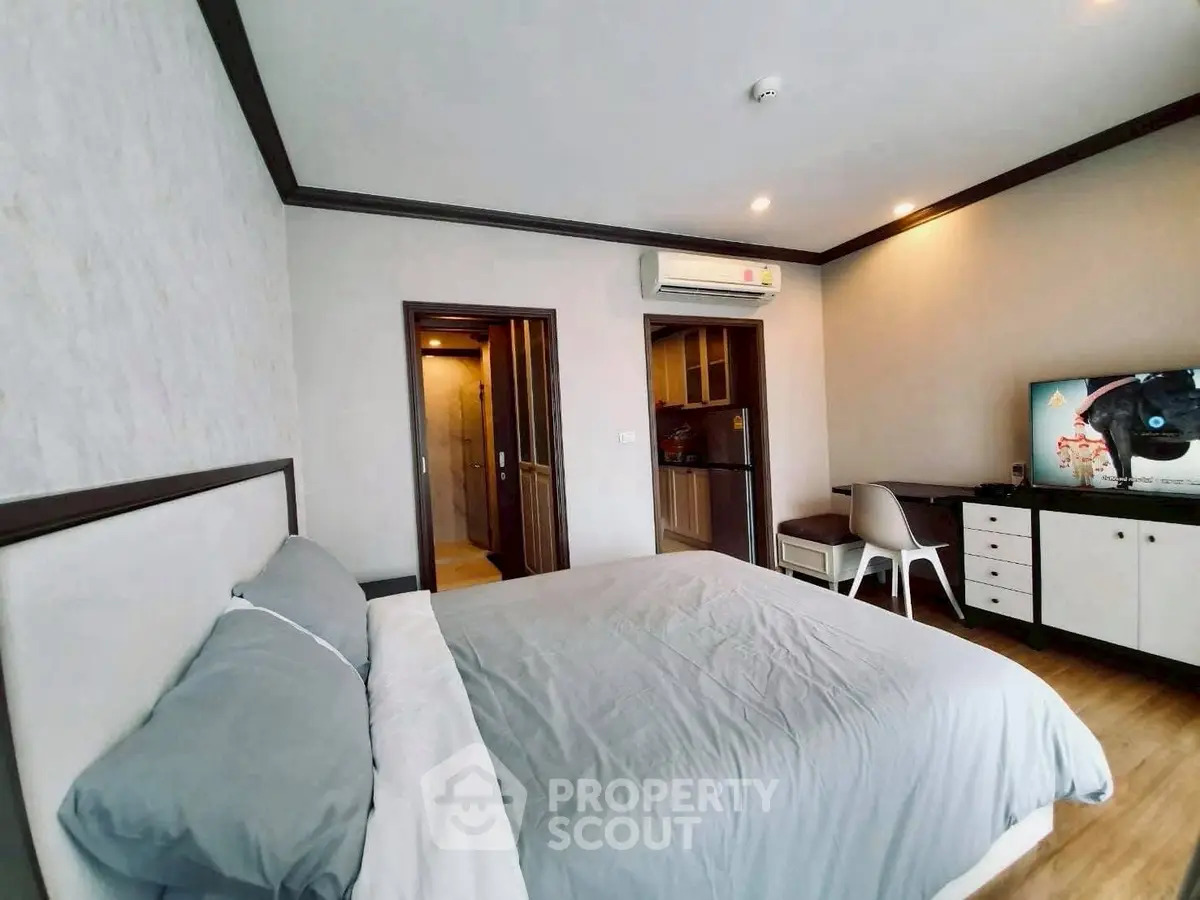 Spacious bedroom with modern decor and adjacent kitchenette in a stylish apartment.