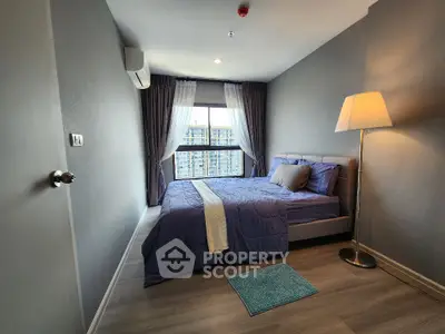 Modern bedroom with stylish decor and large window offering city view