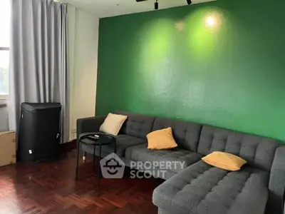 Stylish living room with green accent wall and modern gray sectional sofa.