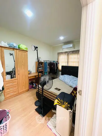 Cozy bedroom with wooden flooring, wardrobe, and air conditioning, perfect for comfortable living.