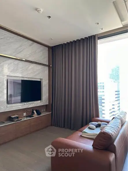 Modern living room with city view, featuring a sleek TV setup and elegant brown sofa.
