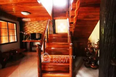 Charming wooden interior with staircase and cozy living area, perfect for rustic home lovers.