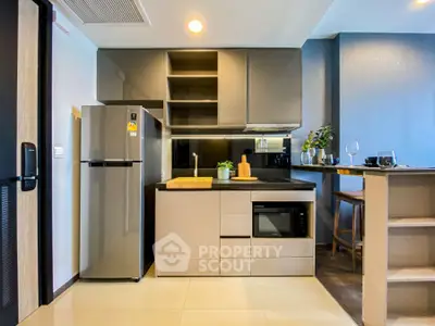 Modern kitchen with sleek cabinetry, stainless steel fridge, and built-in microwave in a stylish apartment.
