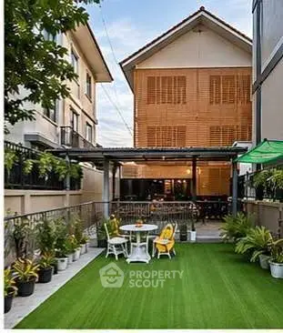Charming outdoor garden space with lush greenery and cozy seating area, perfect for relaxation and entertaining.