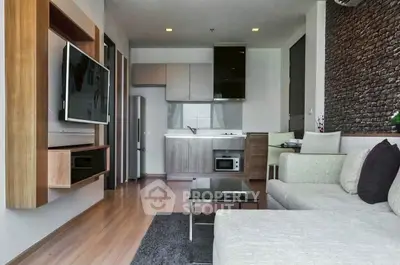 Modern living room with sleek kitchen, featuring open layout and stylish decor.