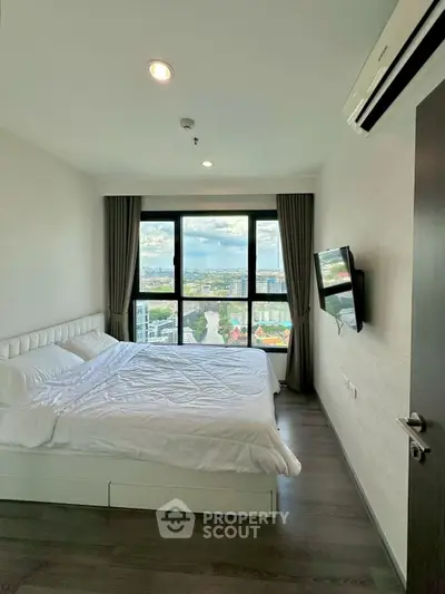 Modern bedroom with large window offering stunning city views, featuring sleek design and cozy ambiance.