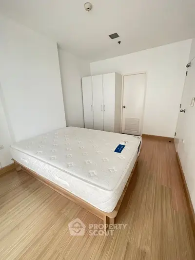 Spacious bedroom with minimalist design and wooden flooring