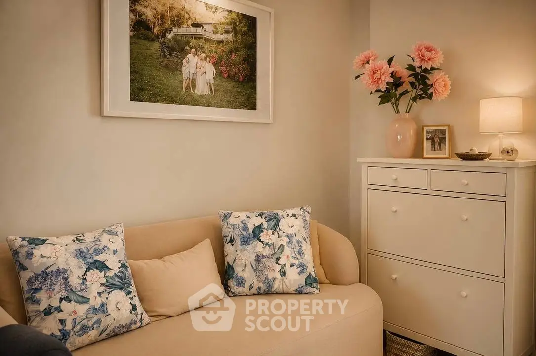 Cozy living room with elegant decor and floral accents, featuring a comfortable sofa and stylish chest of drawers.