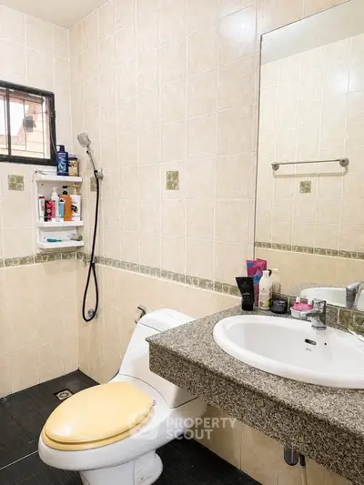 Modern bathroom with sleek fixtures and neutral tiles, featuring a stylish sink and toilet.