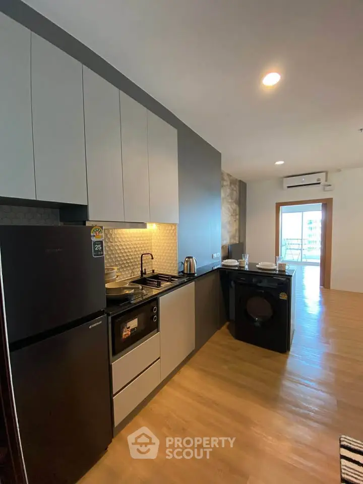 Modern kitchen with sleek cabinets, built-in oven, and washing machine in a stylish apartment.