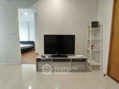 Modern living room with sleek TV setup and open view to bedroom
