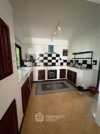 Modern kitchen with checkered backsplash and sleek cabinetry, featuring built-in oven and ample counter space.
