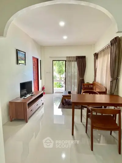 Spacious living room with modern furniture and large windows offering garden views.