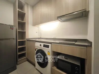 Modern kitchen with washing machine, microwave, and sleek cabinetry