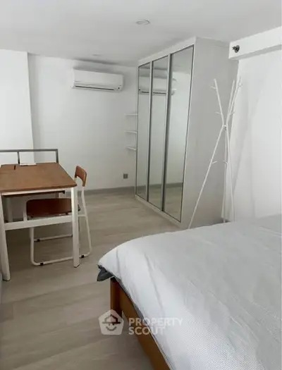 Modern minimalist bedroom with mirrored wardrobe and compact dining area.