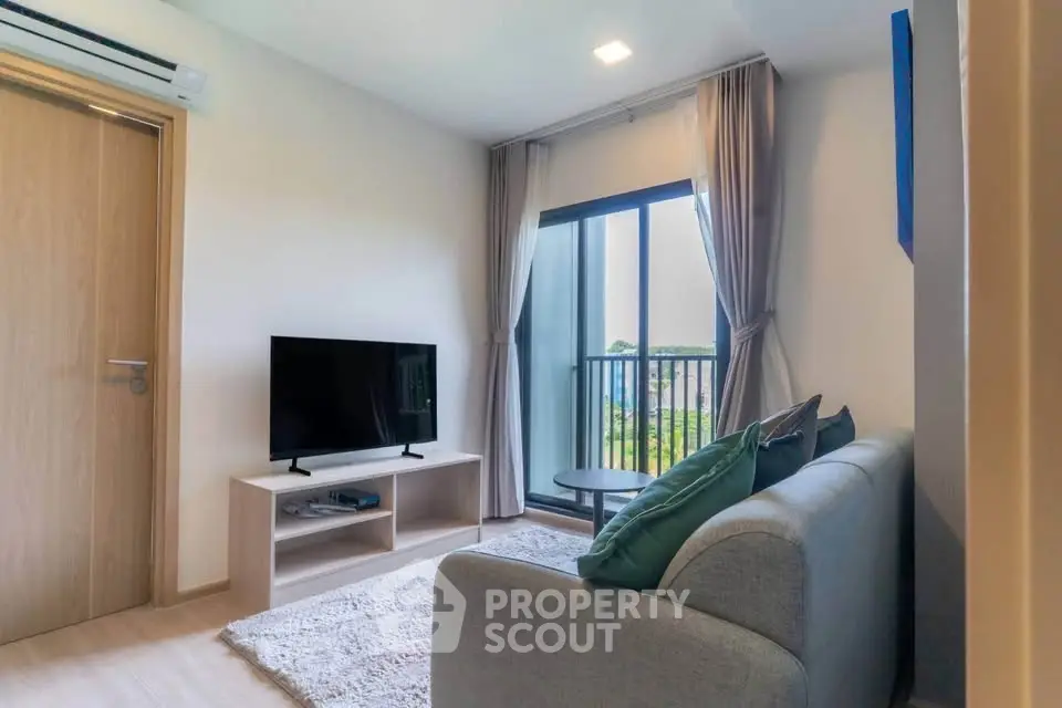 Modern living room with balcony view, cozy sofa, and sleek TV setup.