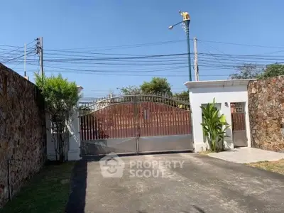 Elegant gated entrance with stone walls and lush greenery, offering privacy and security.