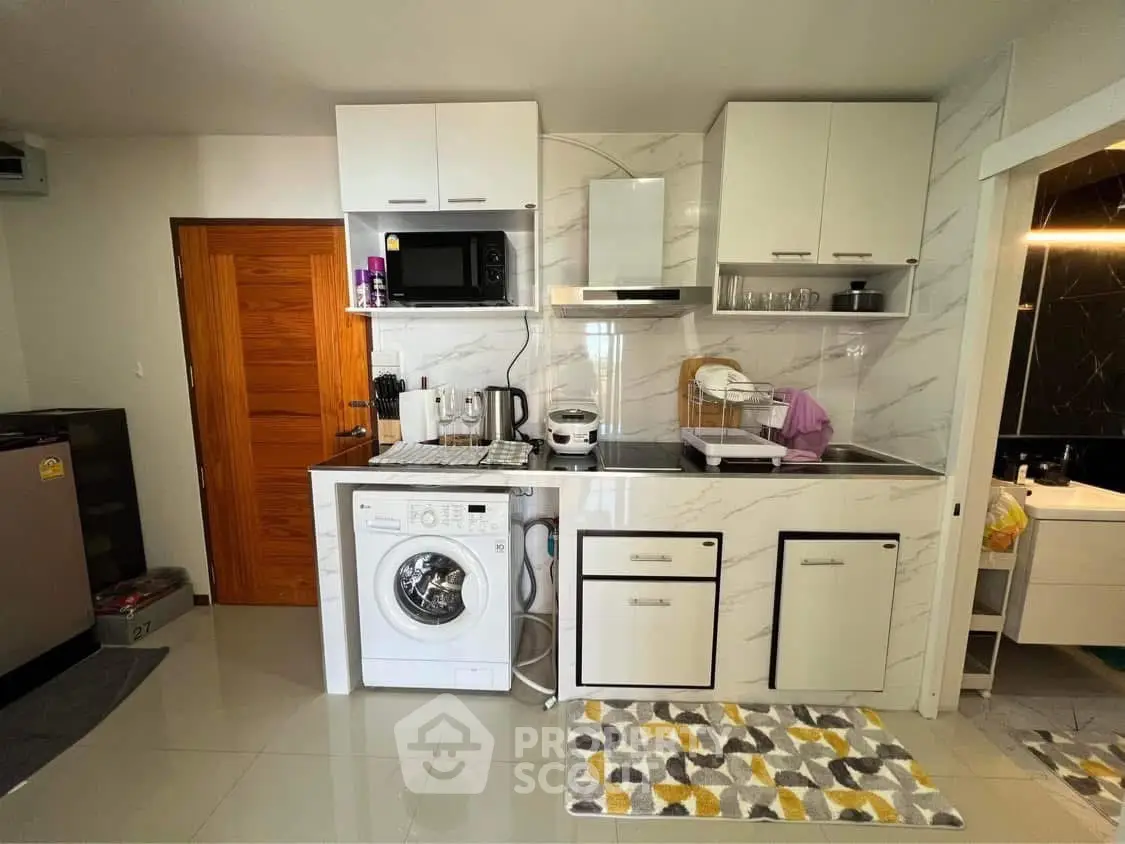 Modern kitchen with washing machine and microwave in compact layout