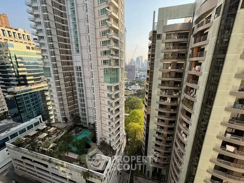Stunning cityscape view of modern high-rise buildings with lush greenery and pool area.