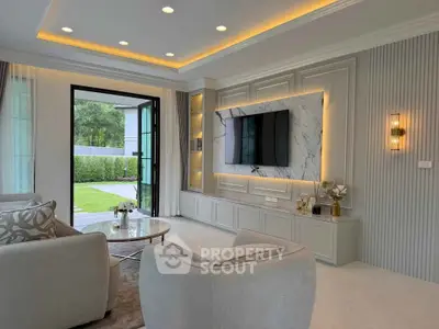 Luxurious living room with modern decor, large TV, and garden view through open glass doors.