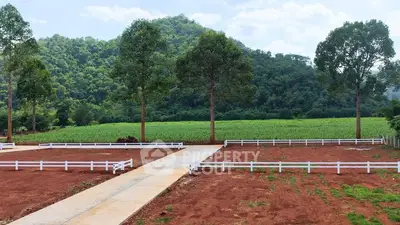 Scenic land plot with lush greenery and mountain backdrop, ideal for development.