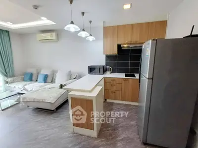 Modern open-layout living room and kitchen with sleek appliances and cozy seating area.