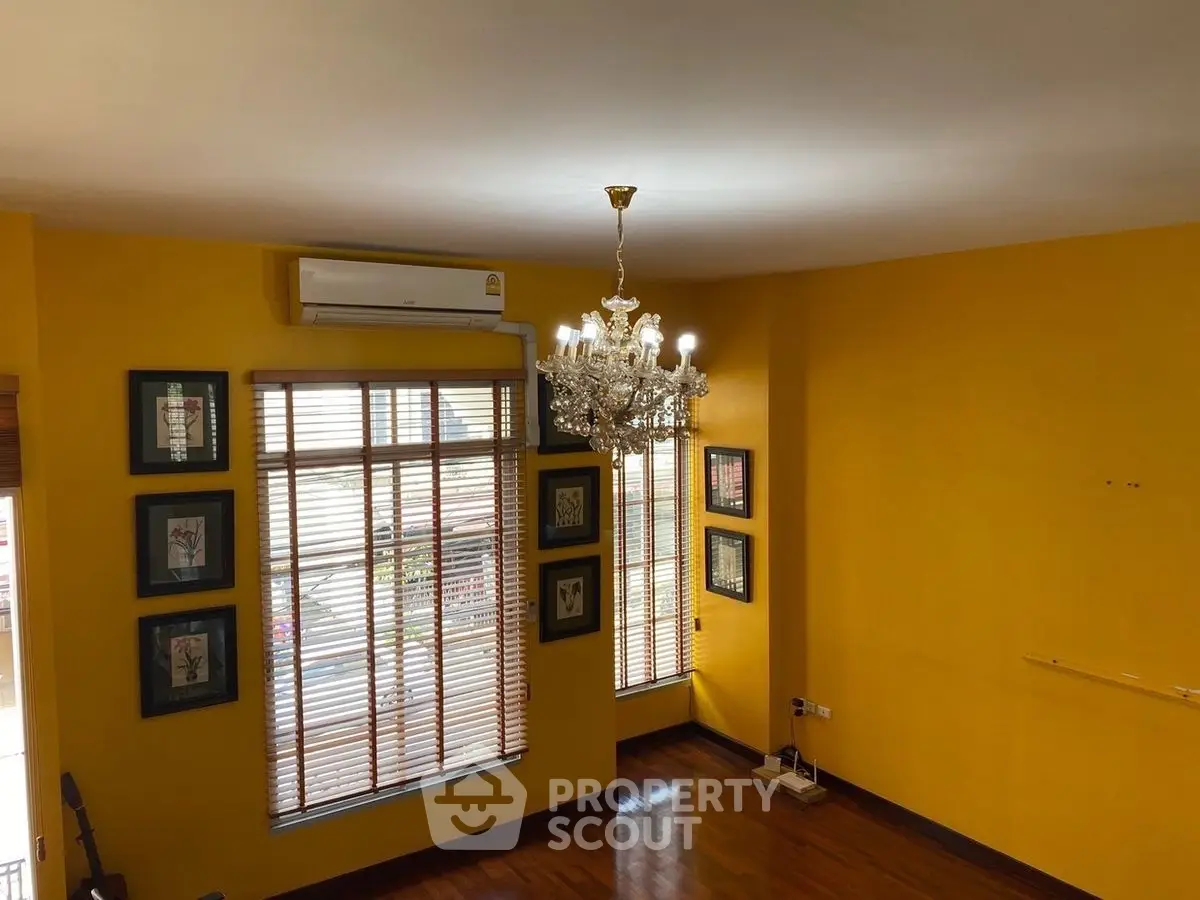 Spacious room with vibrant yellow walls and elegant chandelier