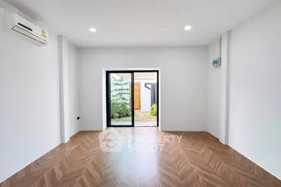 Spacious modern living room with wooden flooring and large glass doors leading to a garden.
