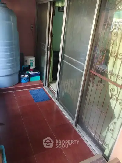 Cozy balcony with sliding glass doors and terracotta tiles, perfect for relaxation.