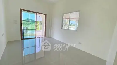 Bright empty room with large windows and glossy tiled floor, offering a serene garden view.