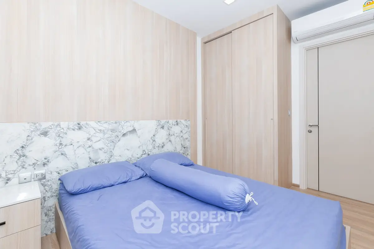 Modern bedroom with stylish marble accent wall and cozy blue bedding