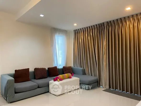 Modern living room with sleek sofa and elegant curtains, perfect for relaxation and entertainment.