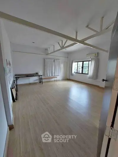 Spacious room with wooden flooring and large windows, ideal for versatile use.