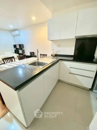 Modern kitchen with sleek white cabinets and black countertops in open layout